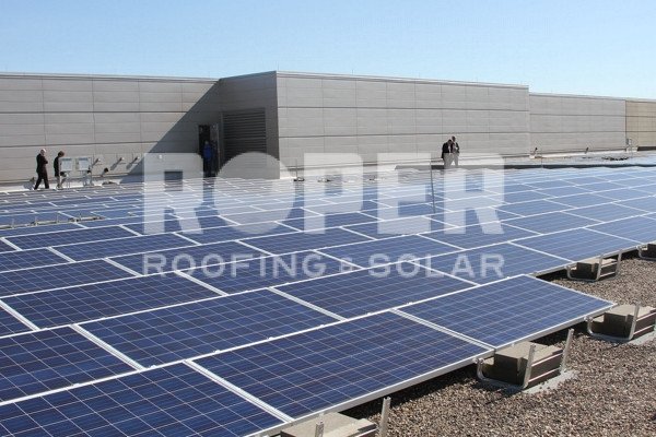 Solar panels installed on commercial building rooftop with workers in background