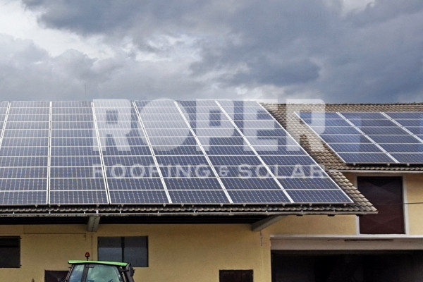 Solar panels installed on residential house roof under cloudy sky