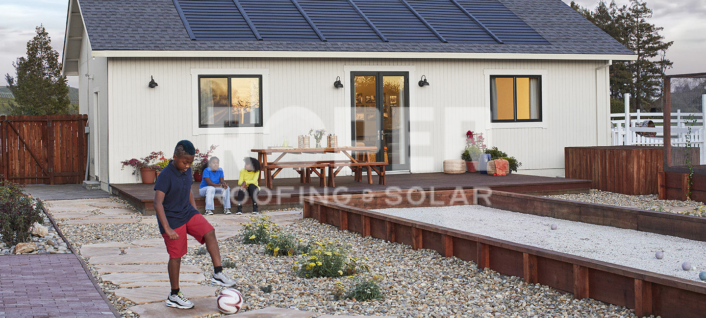 Modern white farmhouse with solar panels and family playing in landscaped yard