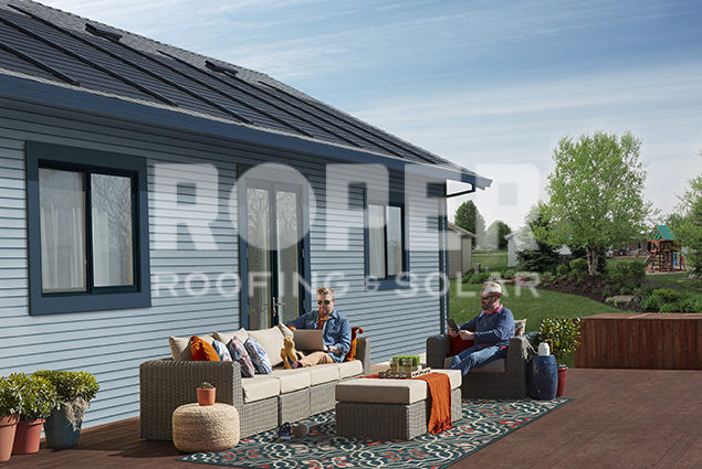 Modern blue house with solar panels and outdoor patio furniture setup