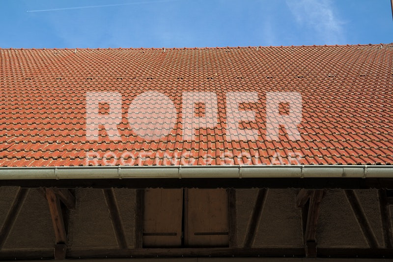 Red clay tile roof with ROPER watermark against blue sky background
