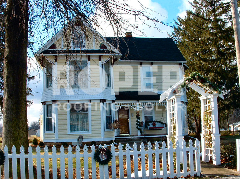 Victorian-style two-story white house with dark roof and white picket fence