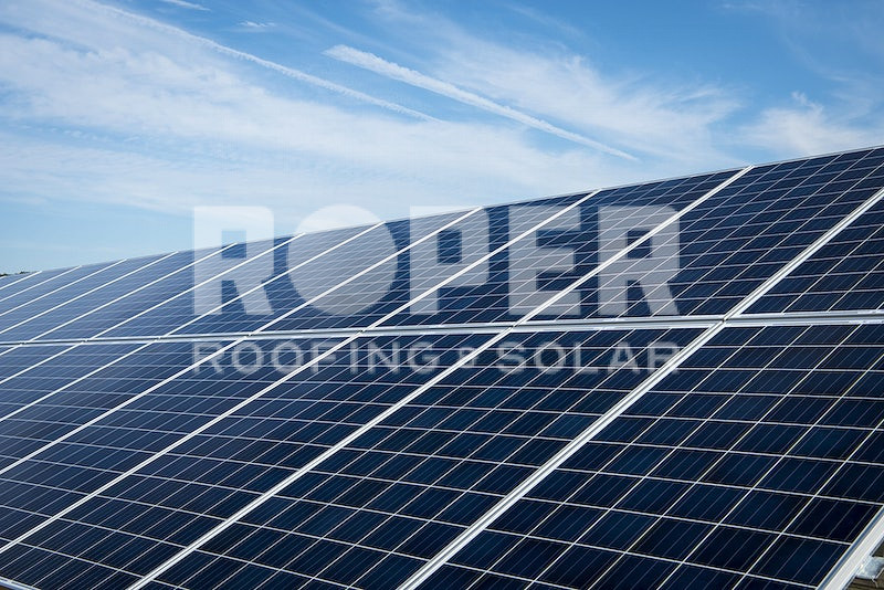 Solar panels arranged in rows under blue sky with white clouds for renewable energy