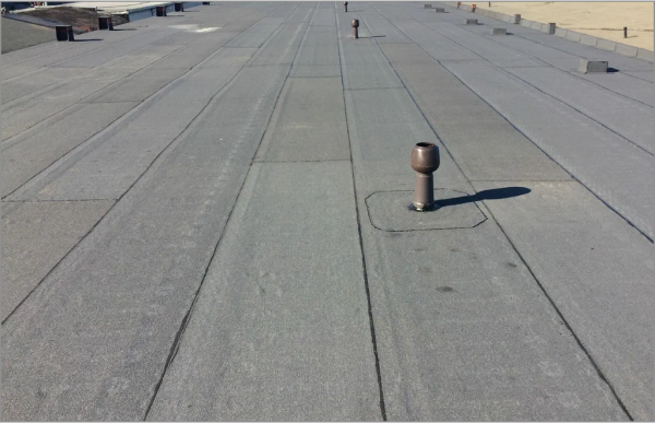 Commercial flat roof with membrane surface and ventilation pipe under sunny sky