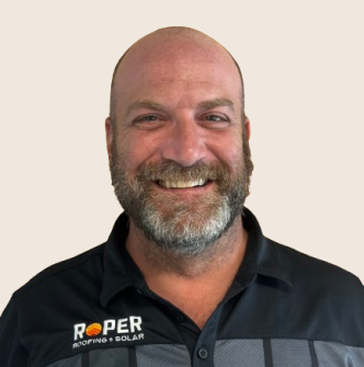 Smiling bald man with gray beard wearing dark Roper polo shirt company uniform