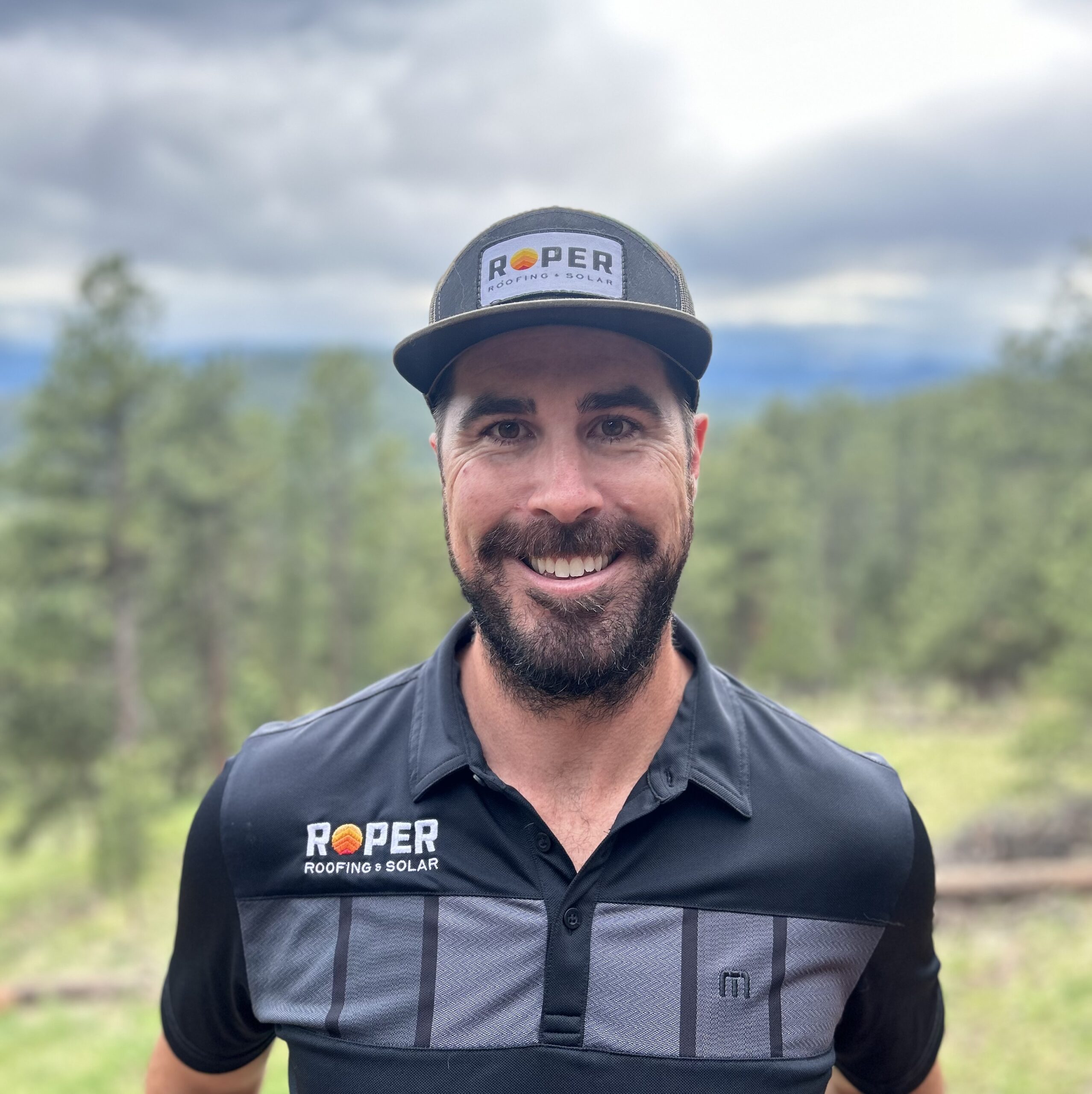 Smiling man in Roper Roofing & Solar branded polo shirt and cap outdoors